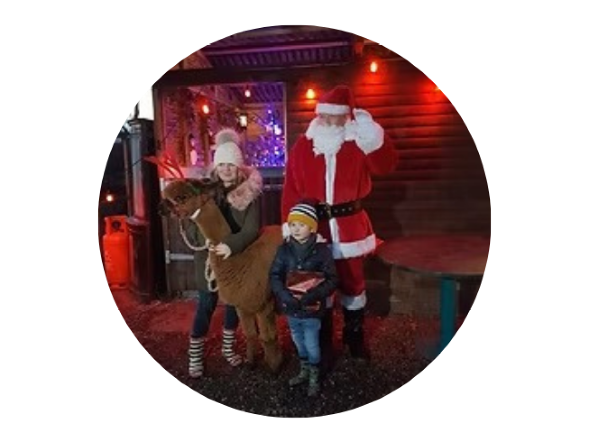 Children posing with Santa Claus and a plush reindeer in a festive setting.